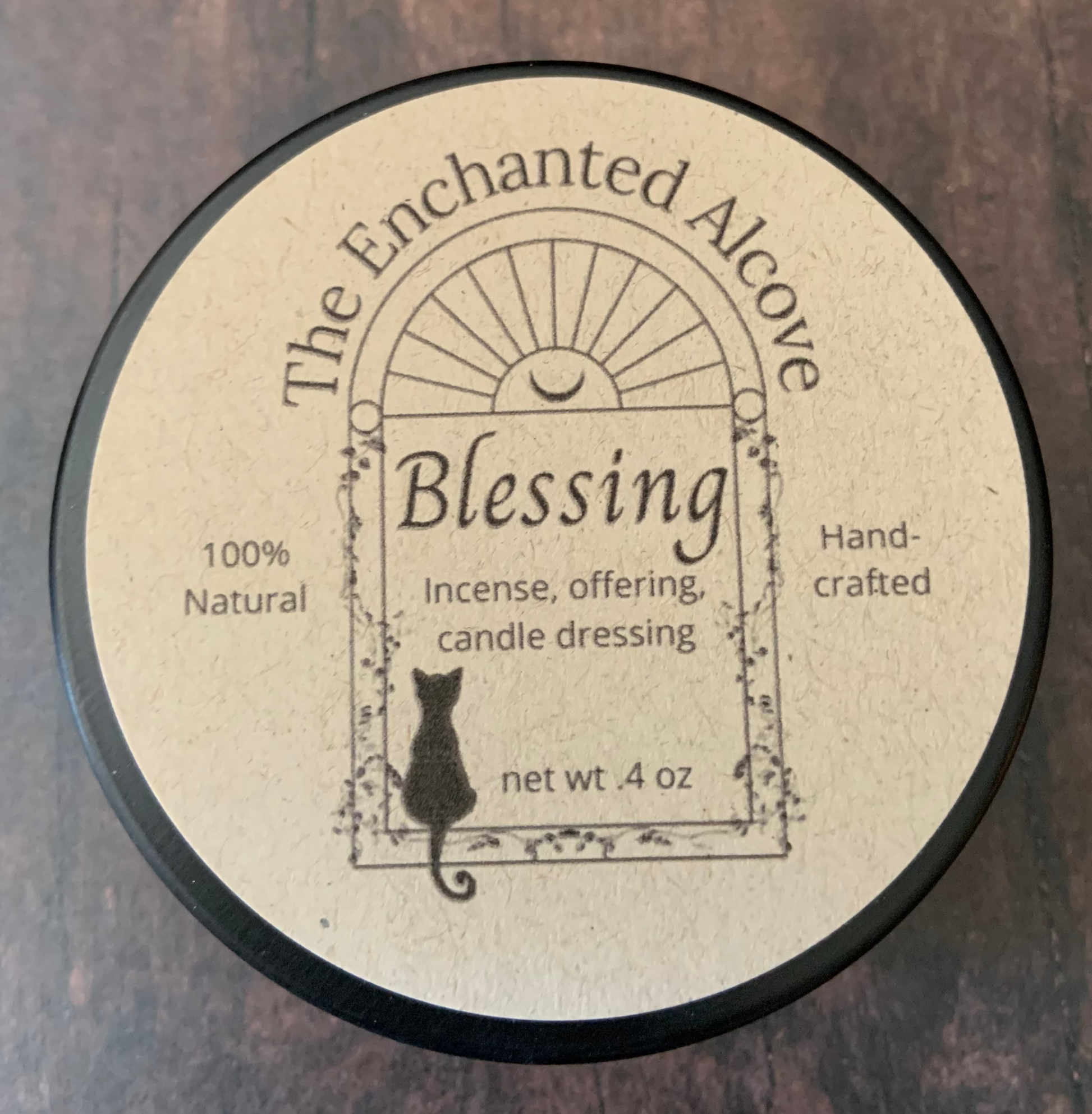 Container of 'Blessing' product from 'The Enchanted Alcove' on a wooden surface